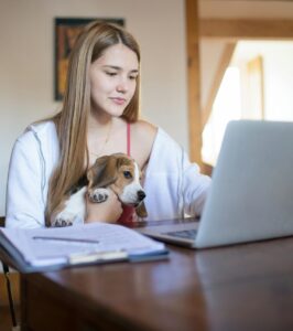 Dog and woman looking at computer at table.
