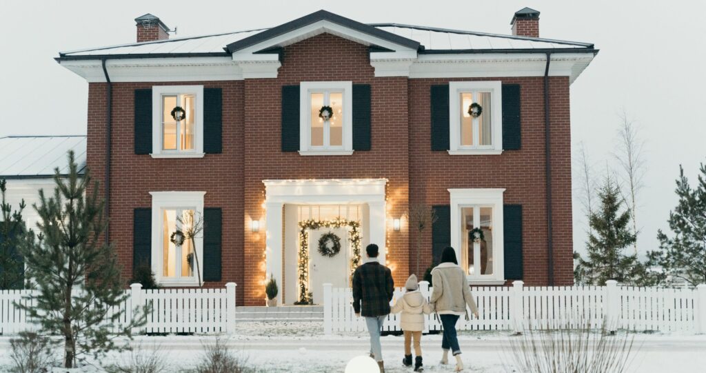 family outside of home decorated with lights for the holidays