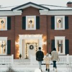 family outside of home decorated with lights for the holidays