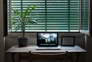 blinds closed on window above desk with laptop